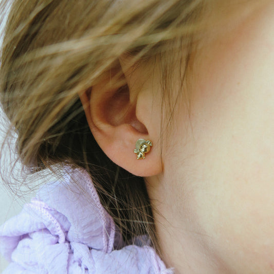 Záběr na ucho dívky s rozkošnou Rubari náušničkou jednorožcem na šroubek.